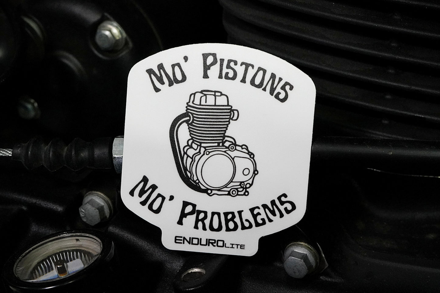 Sticker with engine graphic and text 'Mo' Pistons Mo' Problems' on a mechanical background
