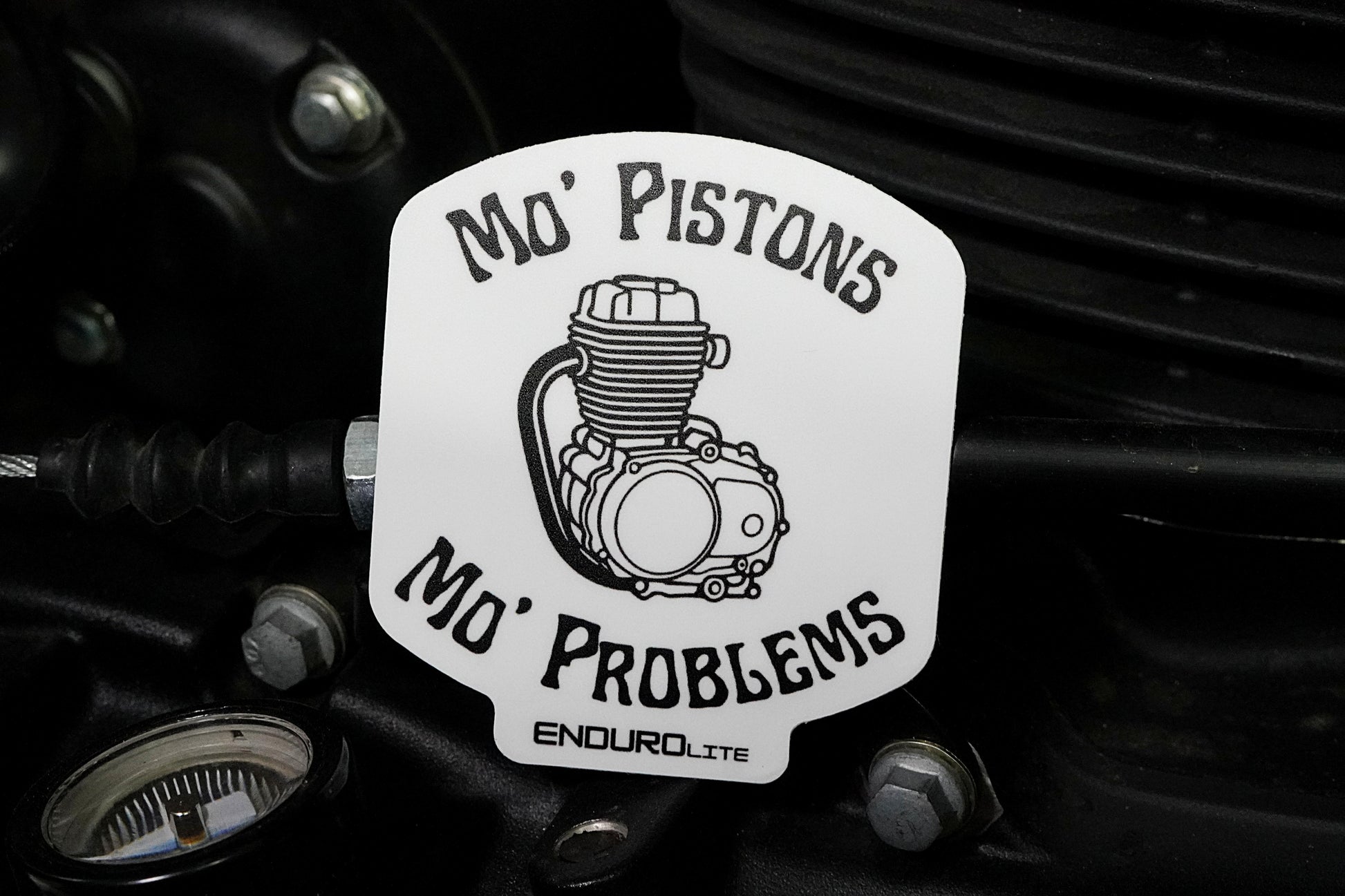 Sticker with engine graphic and text 'Mo' Pistons Mo' Problems' on a mechanical background